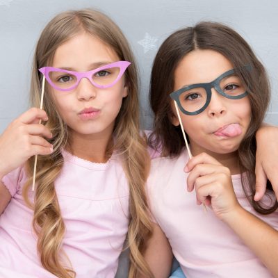Playful mood. Girls children posing with grimaces photo booth props. Pajamas party concept. Girls friends having fun pajamas party. Friends cute and cheerful posing with eyeglasses accessories.